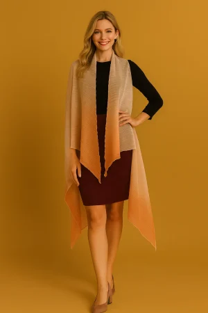 Smiling woman wearing a long peach-to-amber draped shawl over a black top and burgundy pencil skirt, front view on a mustard backdrop.